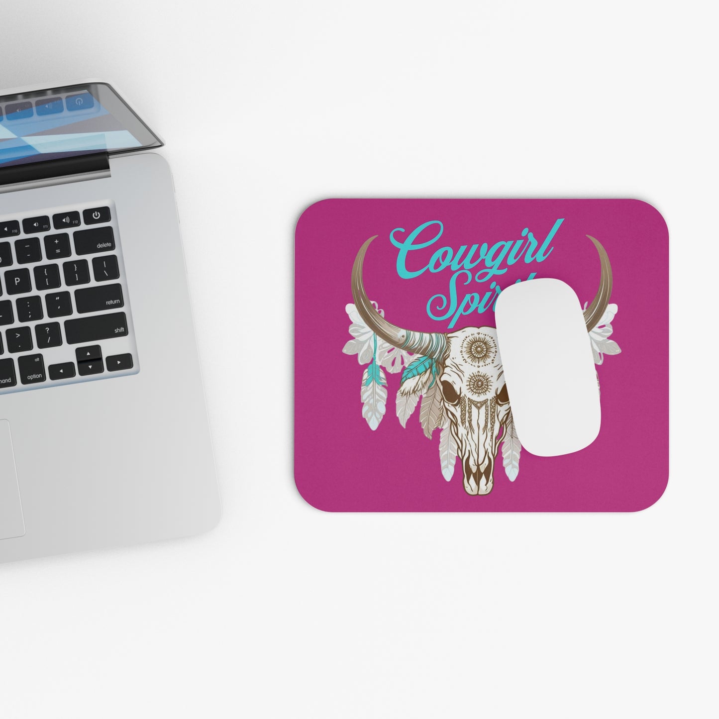 Featuring a striking illustration of a longhorn skull adorned with elegant white and turquoise feathers, this design captures the essence of strength, freedom, and rustic charm. The turquoise cursive lettering above the skull reads "Cowgirl Spirit," adding a touch of Western flair to the design.