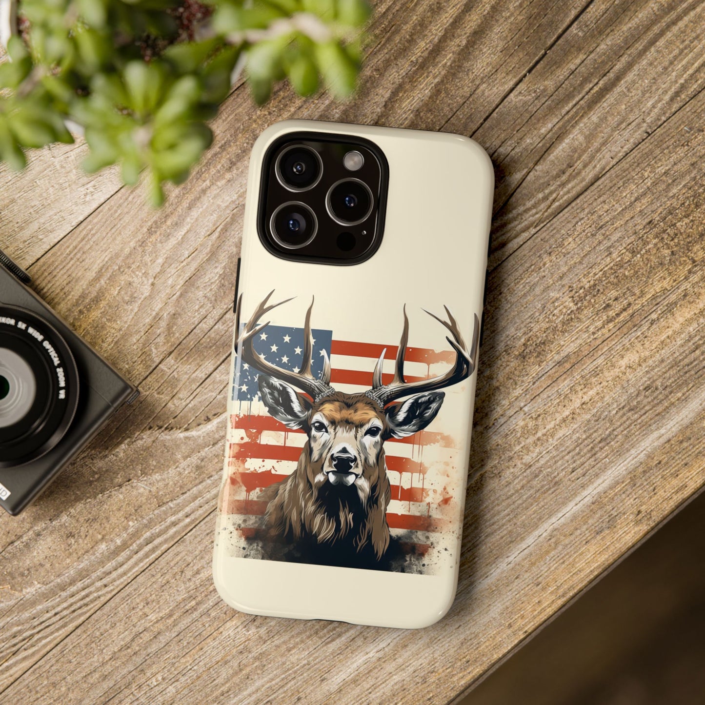 image showcases a detailed illustration of a majestic deer with large antlers, standing proudly in front of a stylized American flag. The flag is artistically rendered with a distressed, splattered effect, adding an artistic touch to the overall design.