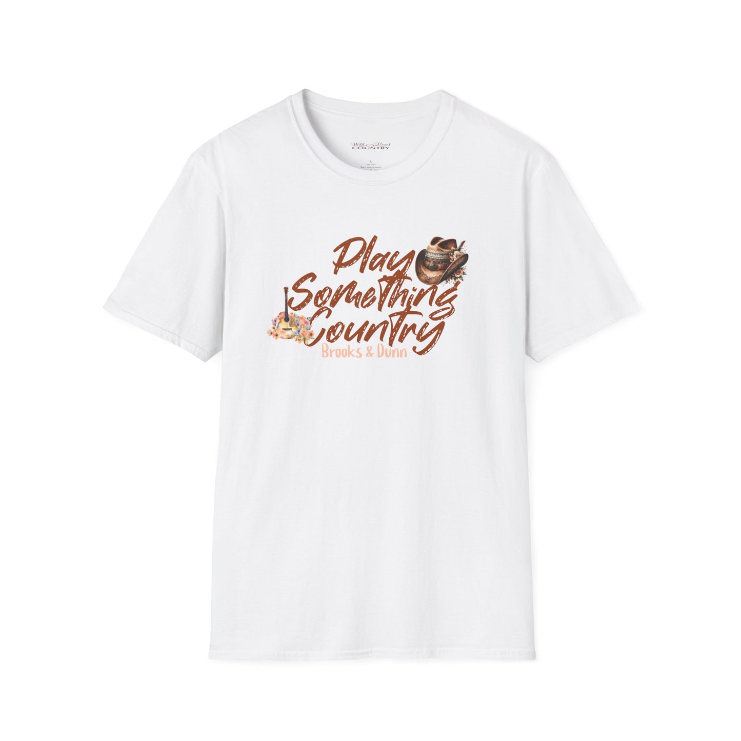 A white t-shirt with the text 'PLAY SOMETHING COUNTRY' and a graphic of a cowboy boot and a guitar on the front, standing in a rural landscape with horses in the background.