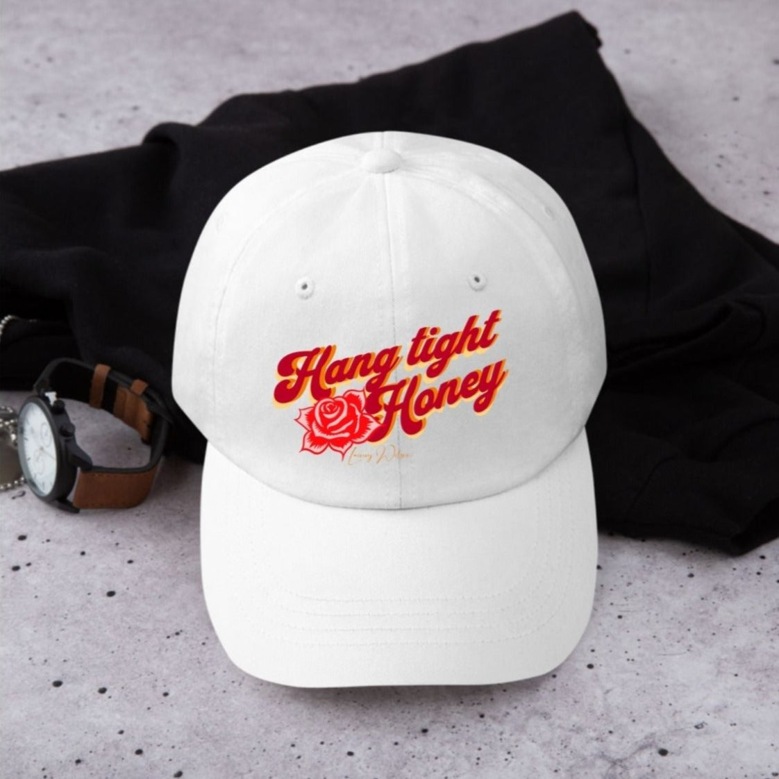 White cap with red, orange and yellow wording "Hang tight honey" written on it