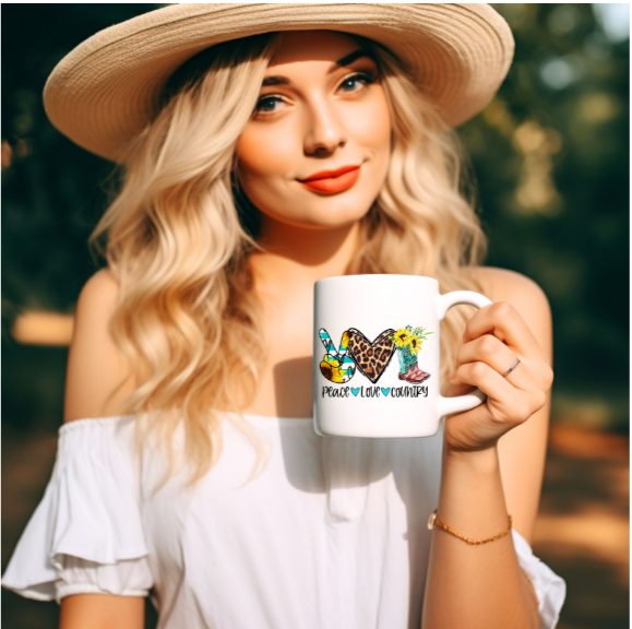 Lady holding a coffee mug with image of peace, love and country on it. Peace is also pictured with the peace symbol of two fingers, there is love heart in leopard print and a pair of cowboy boots.