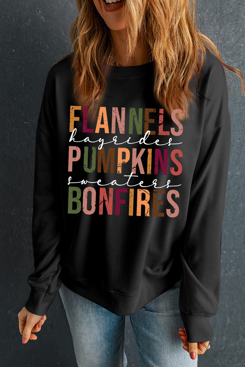 Person wearing a black sweatshirt with colorful text on a dark background