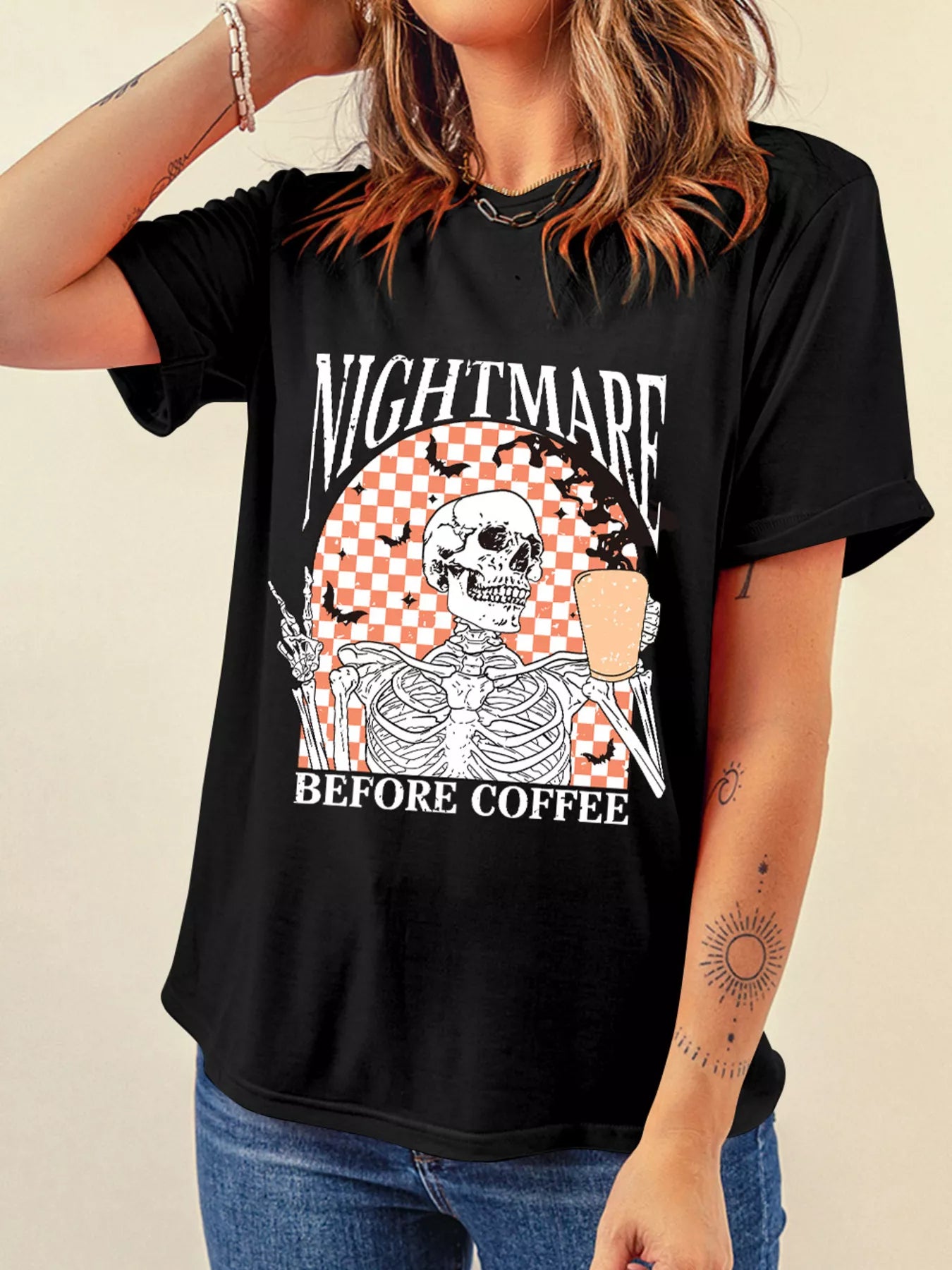 Person wearing a black t-shirt with a skeleton and ice cream graphic and text 'Nightmare Before Coffee'.