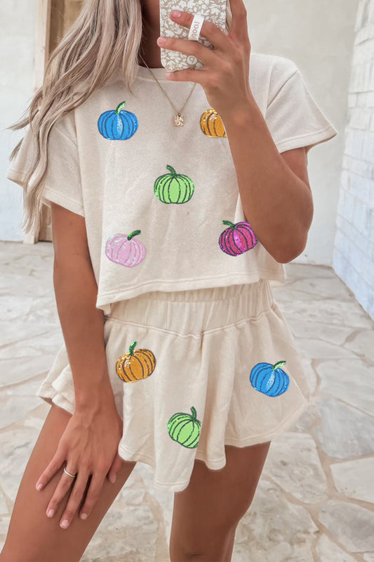 Person wearing a beige outfit with colorful pumpkin designs in a casual setting.