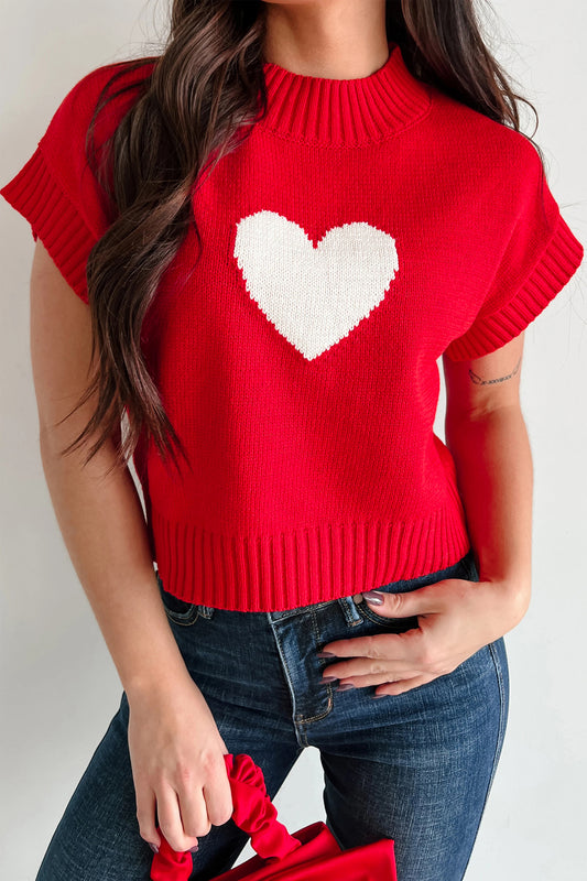 Red sweater with a white heart design worn by a person on a plain background