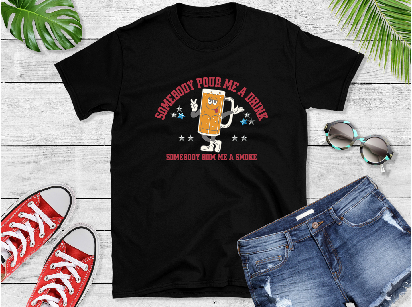Shirt features a lively anthropomorphic beer mug character that’s ready to kick off the good times. Emblazoned with the catchy phrases “SOMEBODY POUR ME A DRINK” and “SOMEBODY BUM ME A SMOKE,” adorned with whimsical stars 