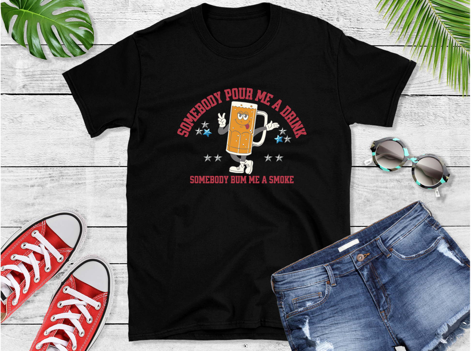 Shirt features a lively anthropomorphic beer mug character that’s ready to kick off the good times. Emblazoned with the catchy phrases “SOMEBODY POUR ME A DRINK” and “SOMEBODY BUM ME A SMOKE,” adorned with whimsical stars 