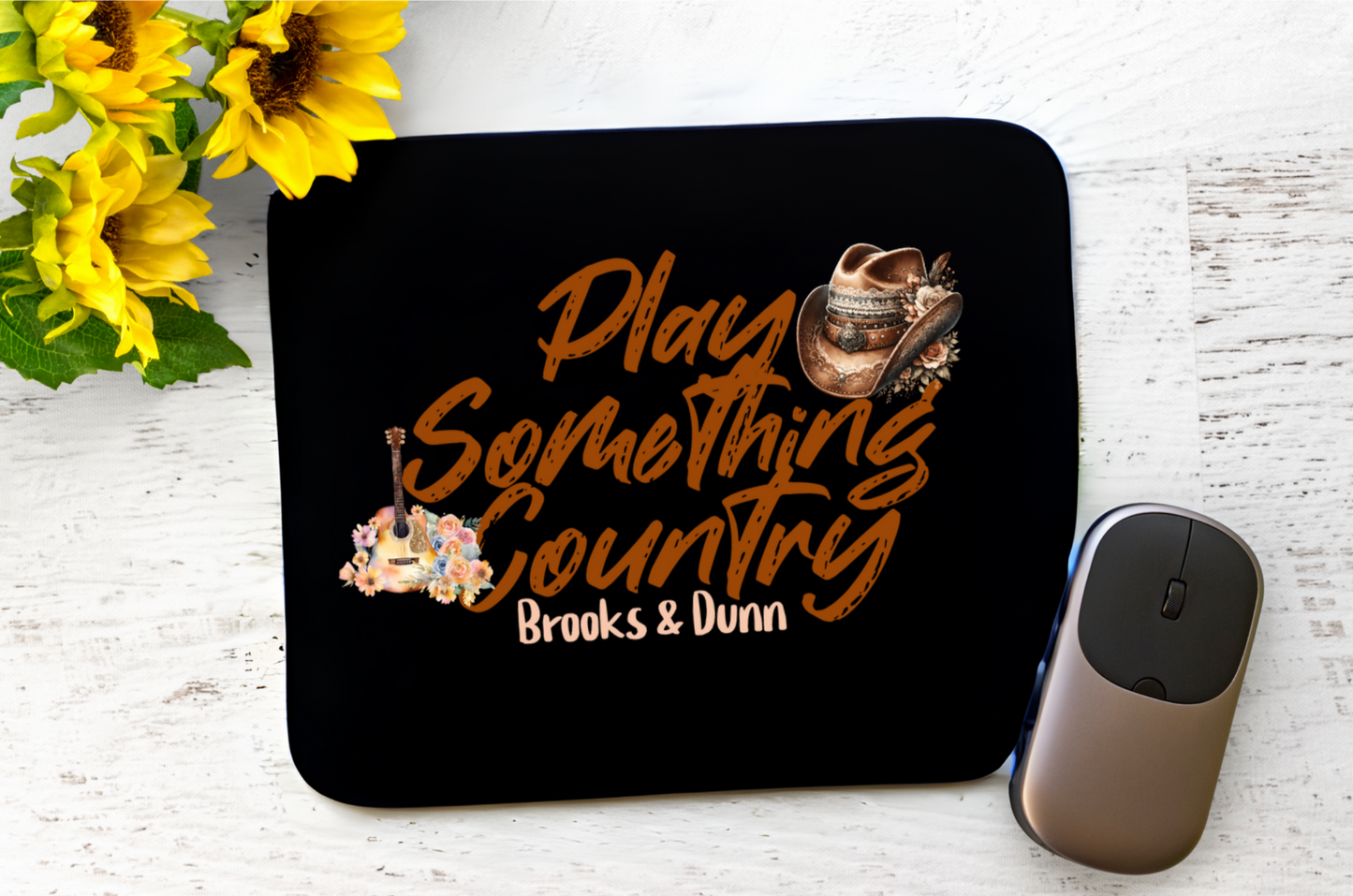 Featuring the phrase “Play Something Country” in a bold, cursive font, this design captures the casual and artistic vibe of the song. Below the text, the name “Brooks & Dunn”. The design is adorned with a rugged cowboy hat on the left. On the right, an acoustic guitar surrounded by a floral arrangement