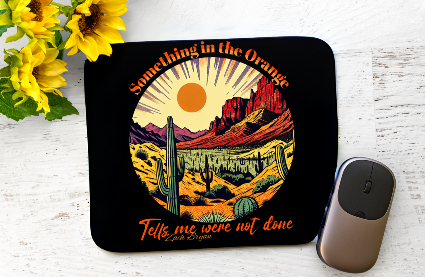 Featuring a stunning desert sunset scene with cacti and mountains, all bathed in a warm orange glow, this mouse pad brings a touch of the wild west to your desk. The lyrics “Something in the Orange” and “Tells me we’re not done” are elegantly displayed