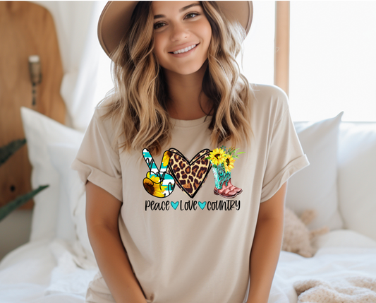 Peace symbol with fingers shaded with sunflower, Love heart shaded with leopard print and pair of cowboy boots with sunflowers coming out the top with "peace Love, Country" written in black text below 