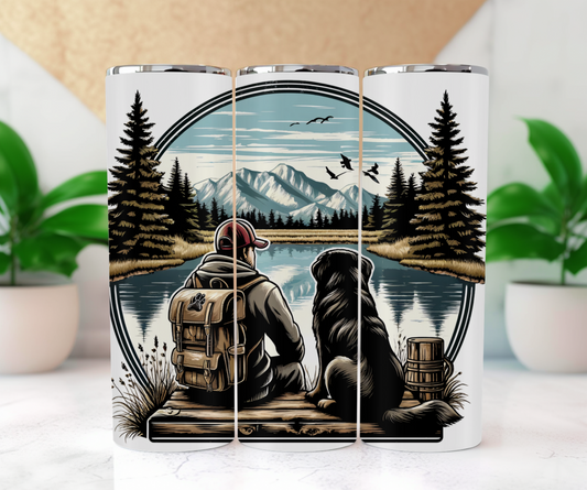 Man and his best friend sitting by a snowy mountain capped lake