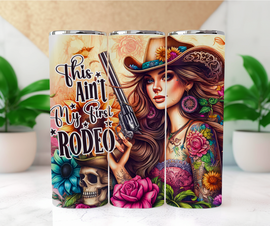 Featuring a stunning cowgirl with tattooed sleeves of colorful flowers, a hat adorned with blooming sunflowers, and a revolver in hand surround by flowers and a skull