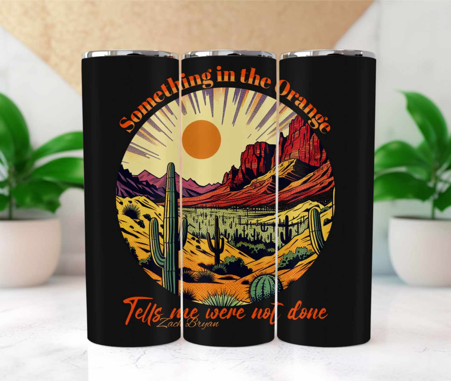 stainless steel bottle features a captivating design of a desert sunset, complete with cacti and mountains, all bathed in a warm orange glow. 