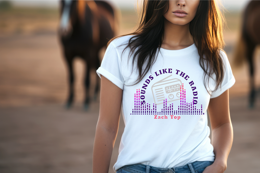This stylish tee features a retro radio graphic at its center, surrounded by vibrant, colorful sound waves that evoke the essence of music. The phrase "SOUNDS LIKE THE RADIO" arches above the radio, while "Zach Top" is prominently displayed below