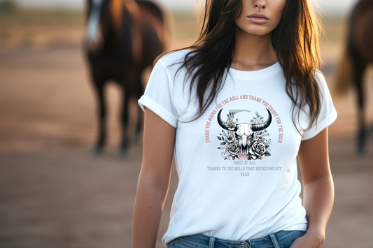 At the center, a bold skull with prominent horns symbolizes strength and defiance, surrounded by an intricate floral pattern that adds a touch of elegance.&nbsp; Above the skull, the text reads, “Thank you mama for the roll and thank you dad for the rock,” while below it states, “Most of all thanks to the bulls that bucked me off yeah”