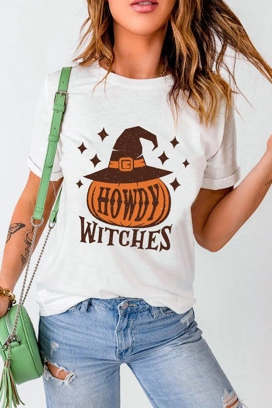 Person wearing a white t-shirt with 'Howdy Witches' graphic design, holding a green handbag.