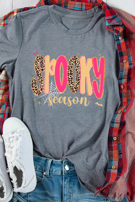 Gray t-shirt with 'Spooky season' text in pink and leopard print, worn with plaid shirt and jeans.