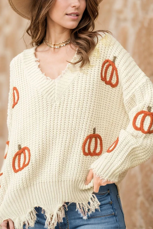 Woman wearing a cream sweater with orange pumpkin patterns against a beige background