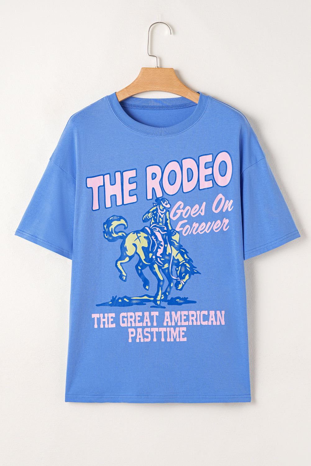 Blue t-shirt with rodeo graphic and text on a hanger against a white background