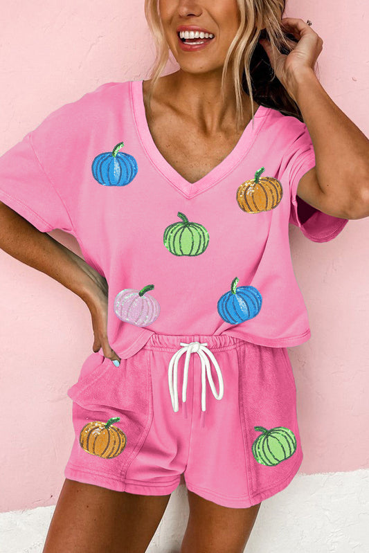 Woman wearing a pink pajama set with colorful pumpkins on a pink background